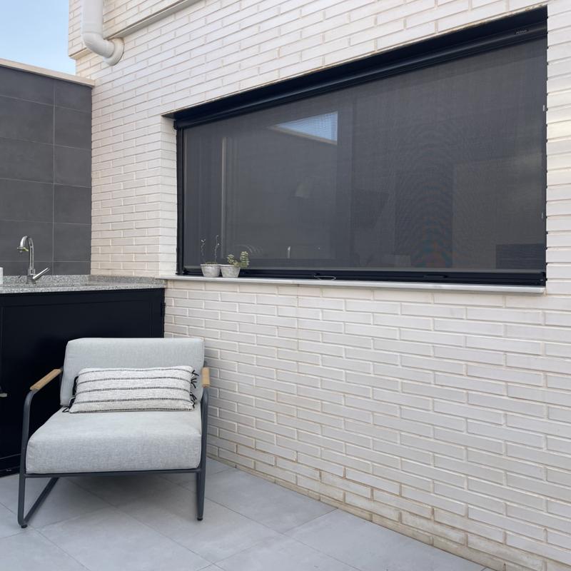 Roller insect screen with a dark frame fitted to a terrace window